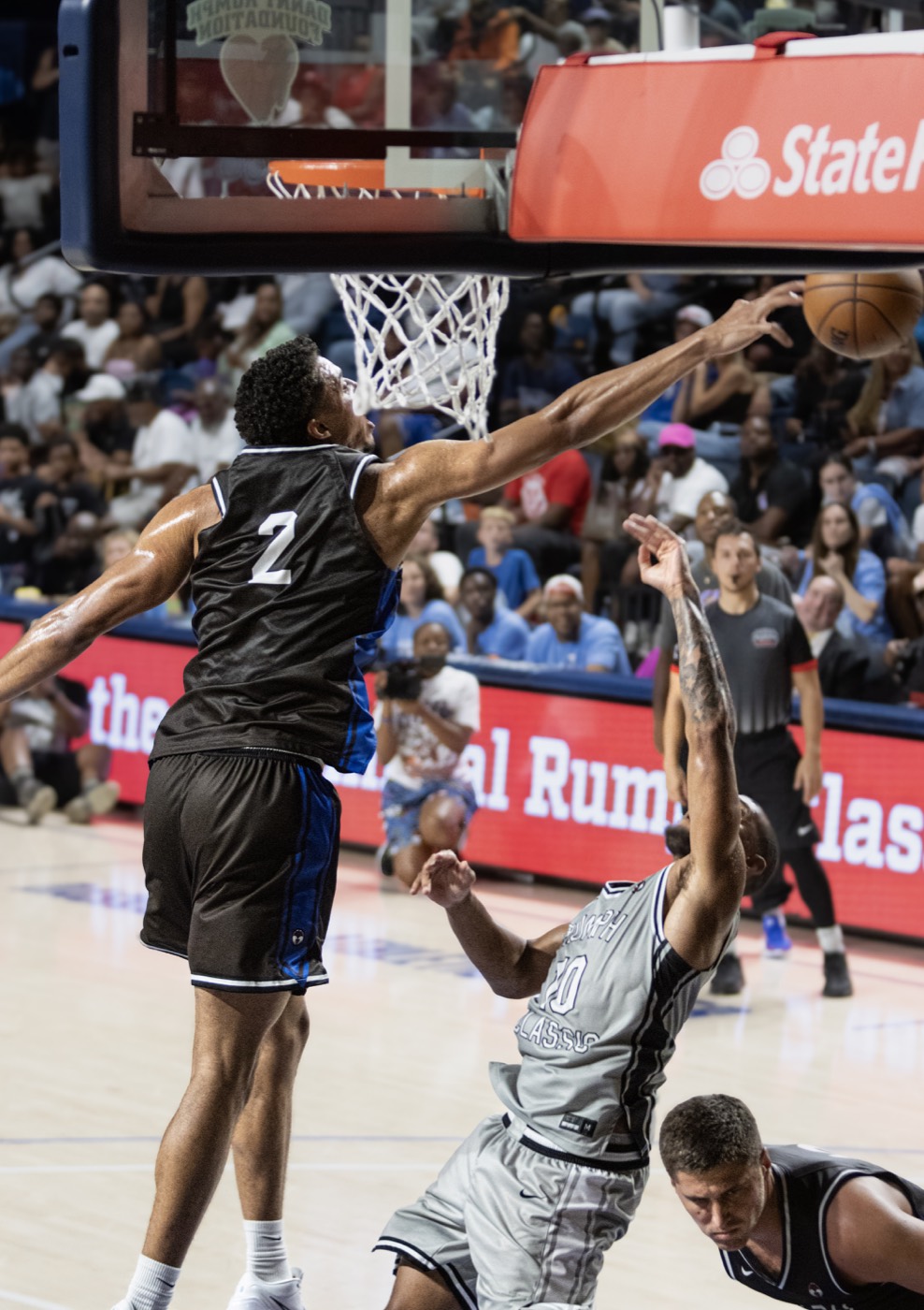 Rumph Classic basketball player extending for a contested finish at the rim
