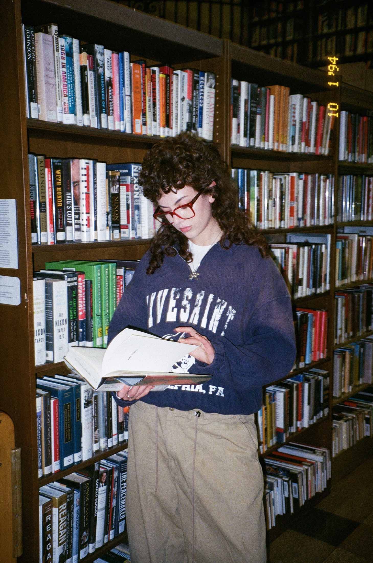 Fith and Saint model reading beside library shelves