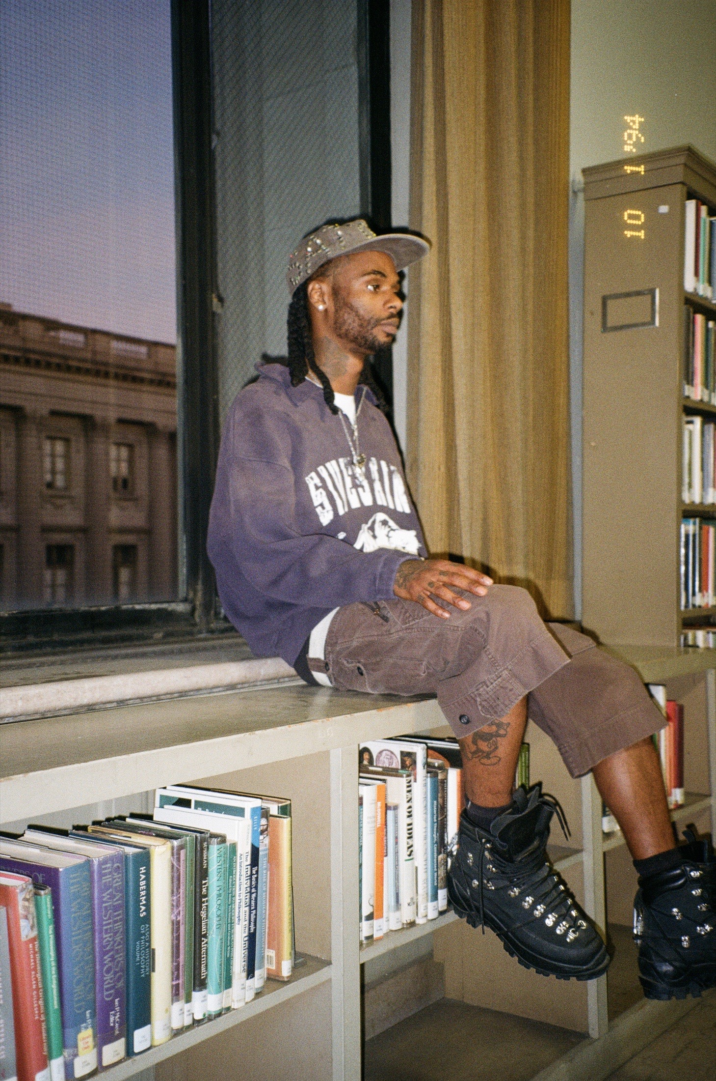 Fith and Saint model seated by a library window