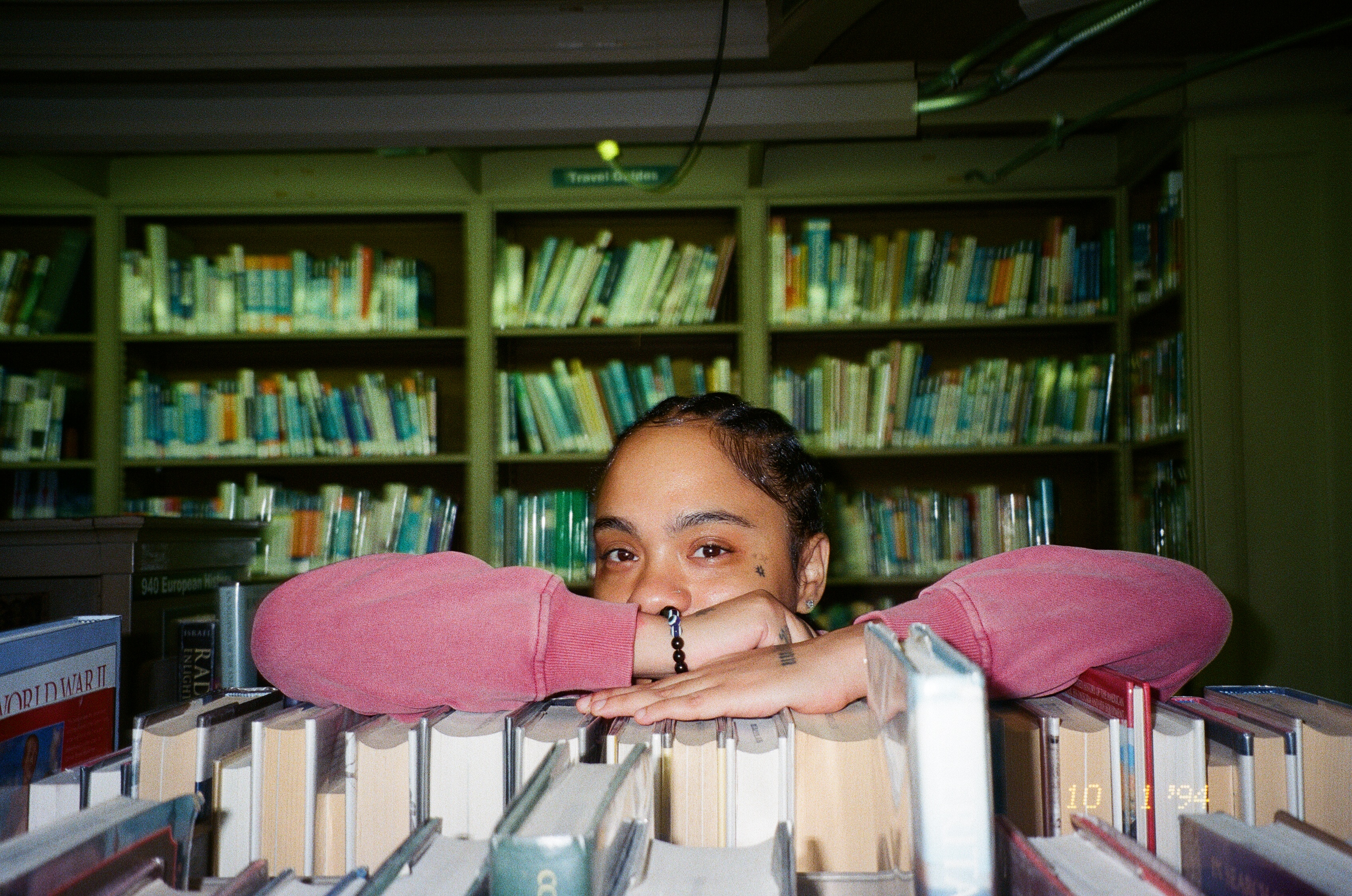 Fith & Saint pink sweatshirt portrait behind books