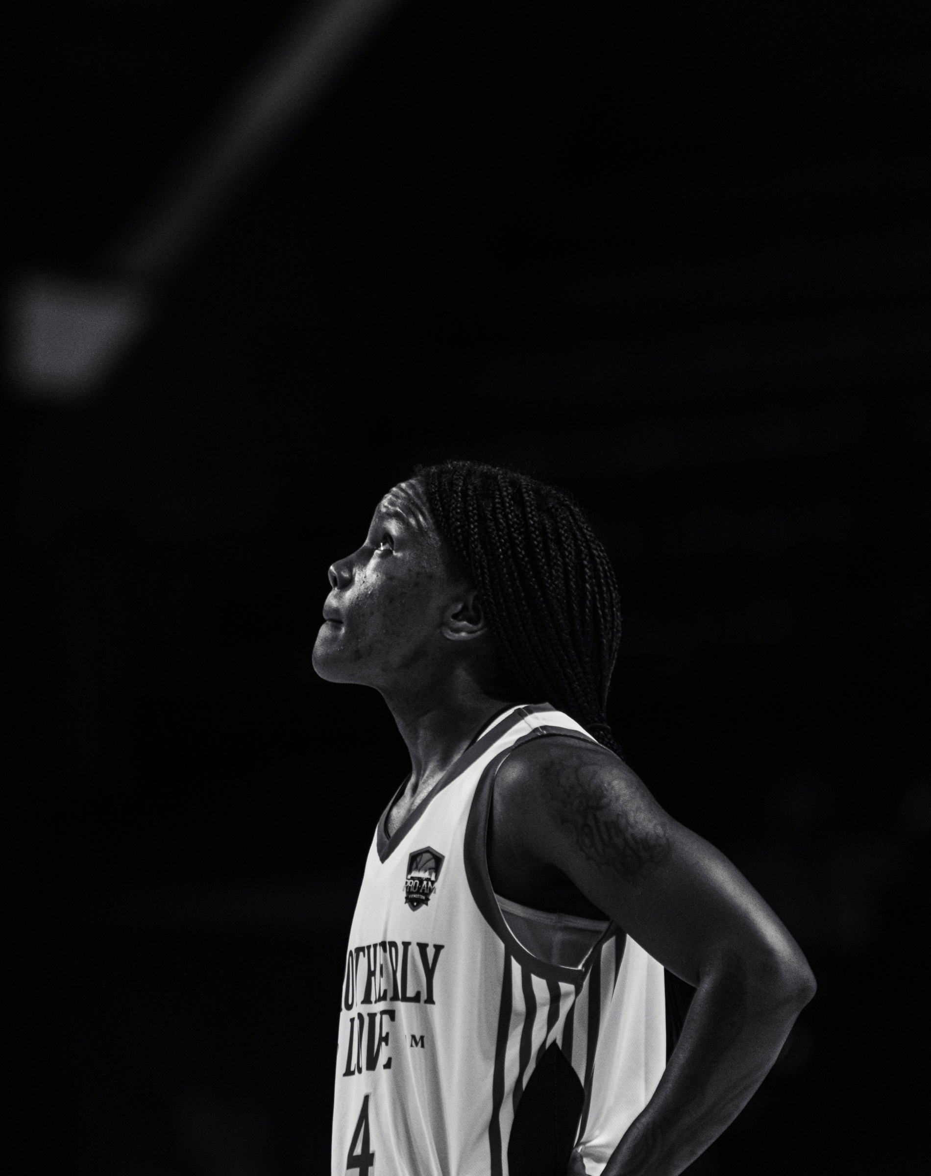 Black and white portrait of a basketball player looking into the arena lights