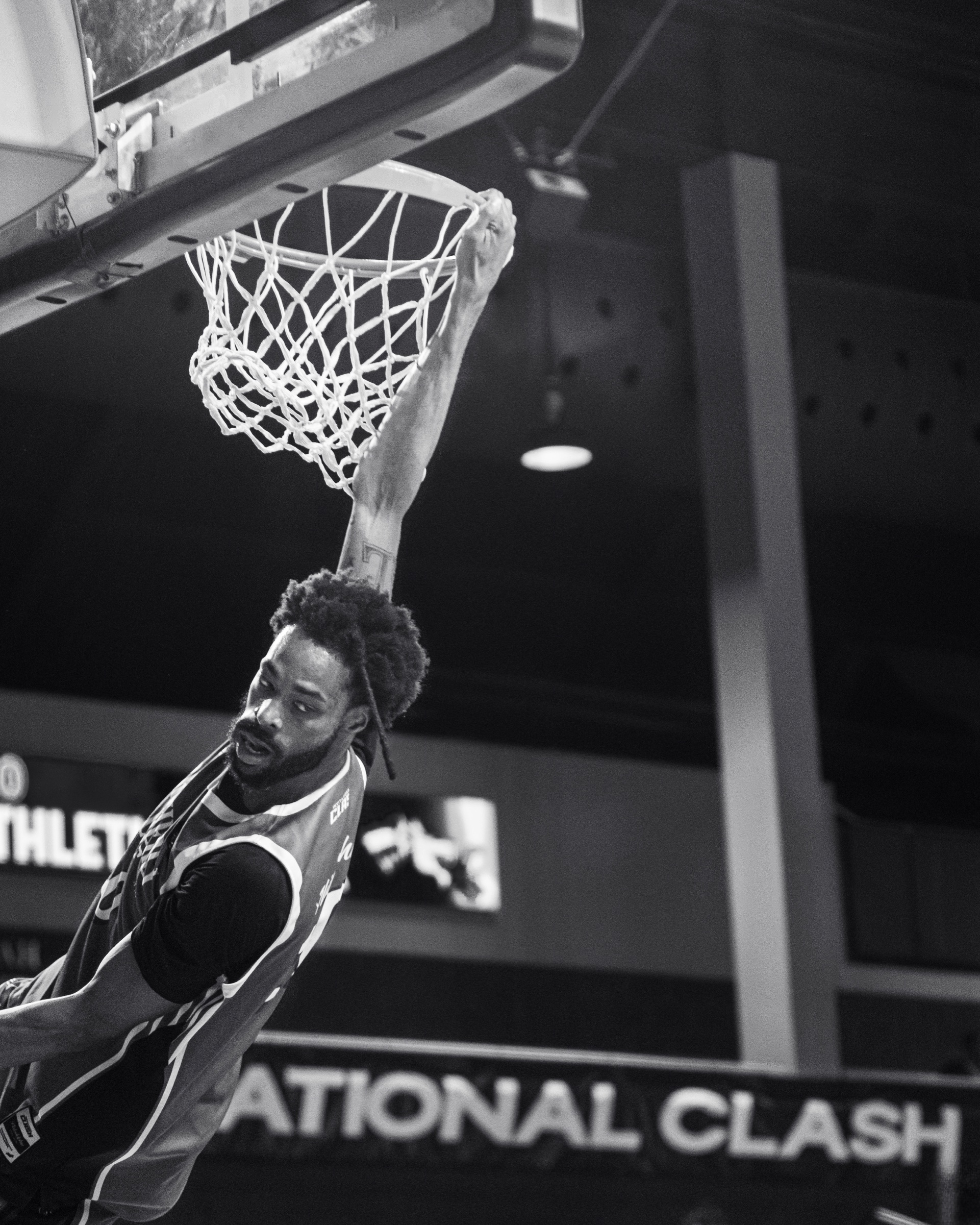 Black and white player hanging from the rim after a dunk