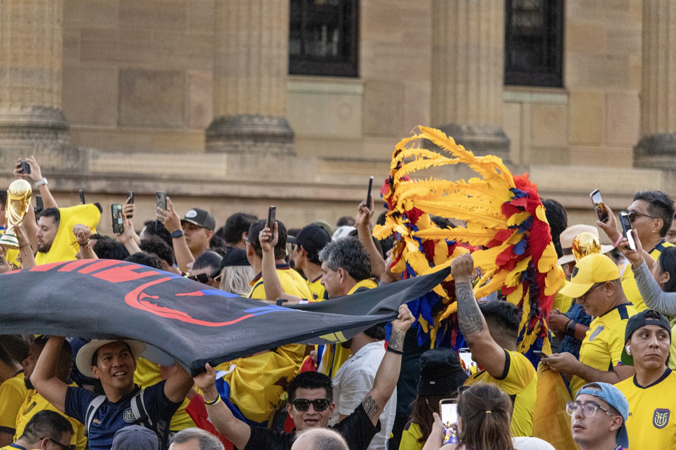 Ecuadorian crowd with yellow red and blue fan headpiece